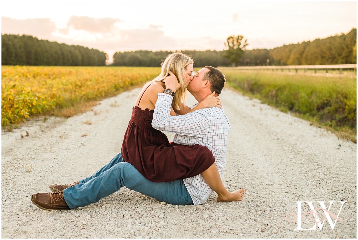 Engaged couple sitting in the middle of the road kissing on the farm in Currituck, NC, taken by Laura Walter Photography.