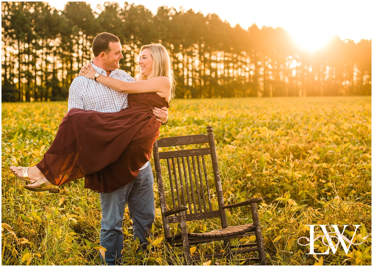 Engaged couple standing next to a rocking chair at sunrise on the farm in Currituck, NC taken by Laura Walter Photography.