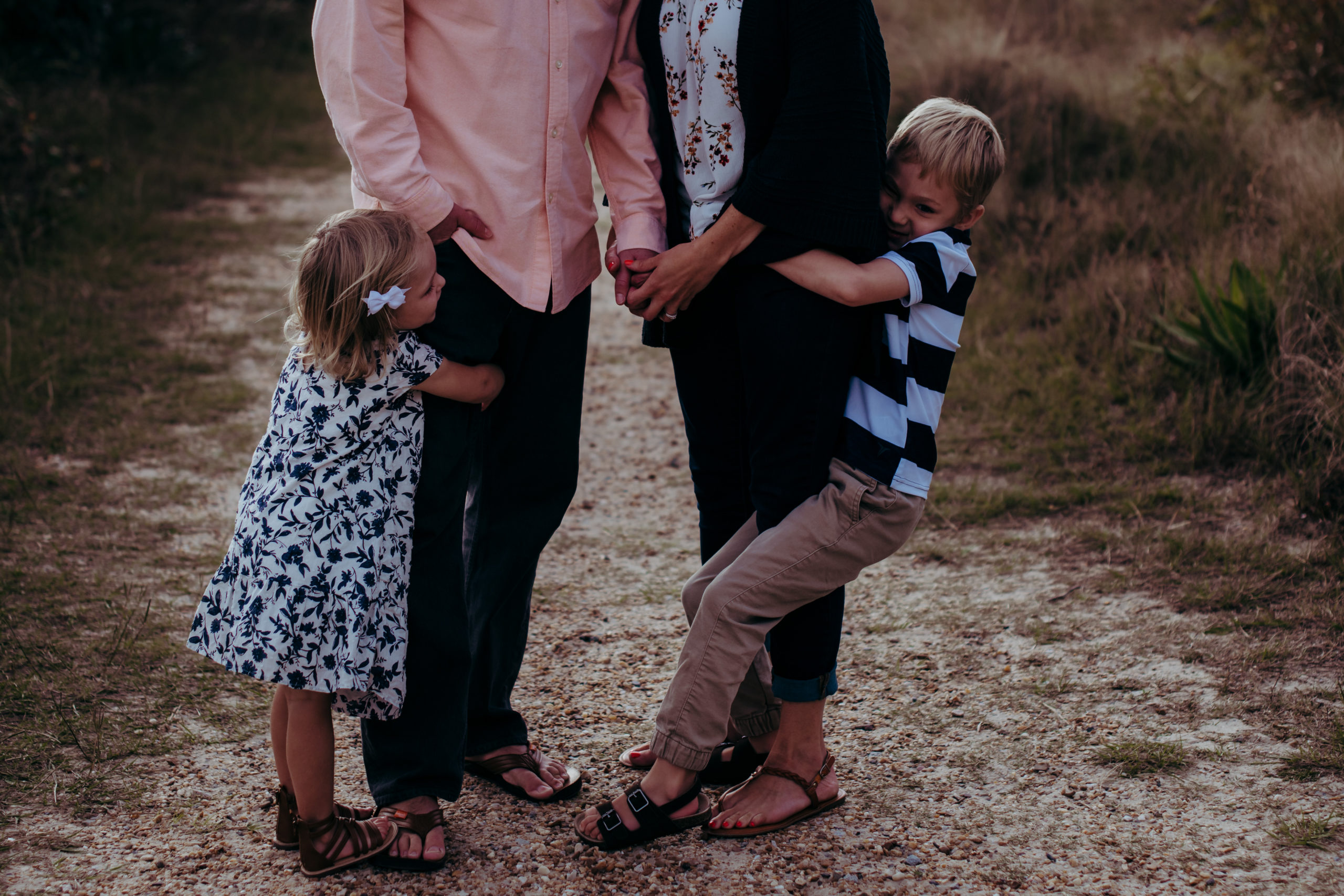 brother and sister hugging mom and dads legs by laura walter photography