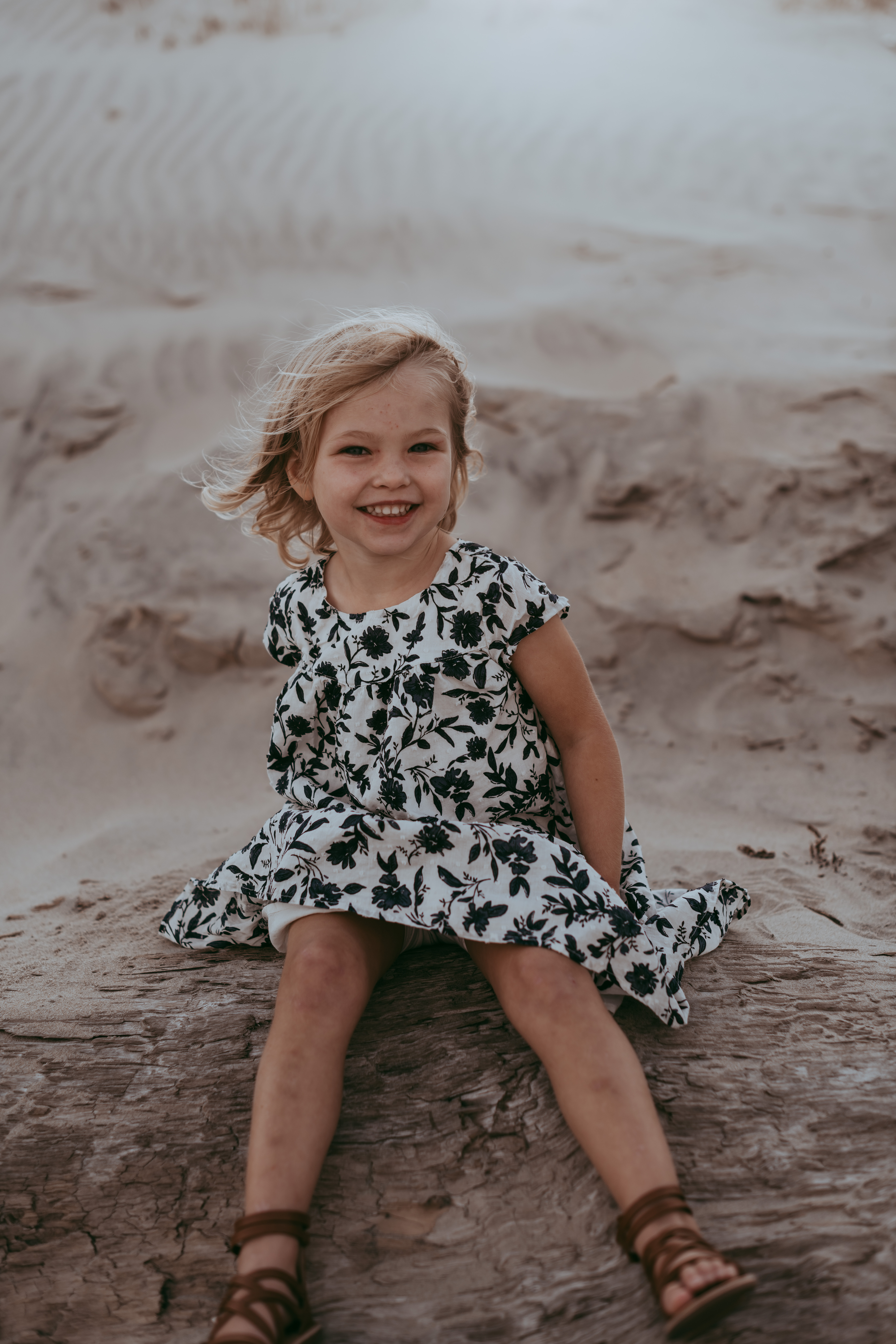 sweet little girl on tree trunk in the sand by Laura Walter Photography