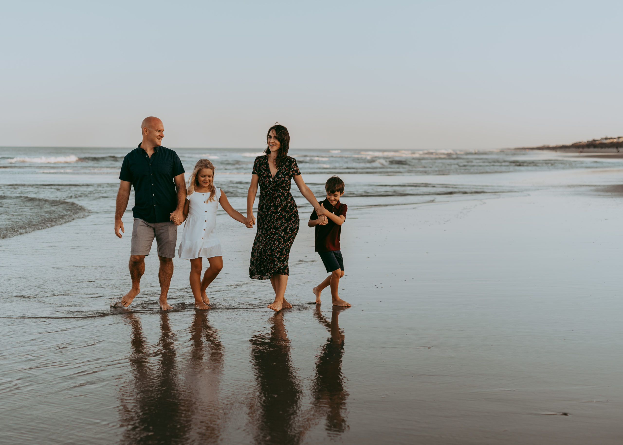 Family Photo Sessions in Corolla by Laura Walter Photography holding hand walking by the water
